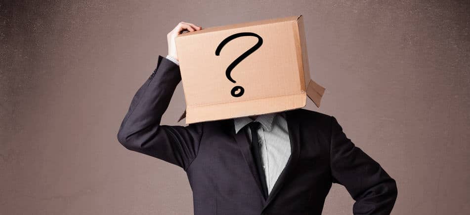 Businessman gesturing with a cardboard box on his head with ques